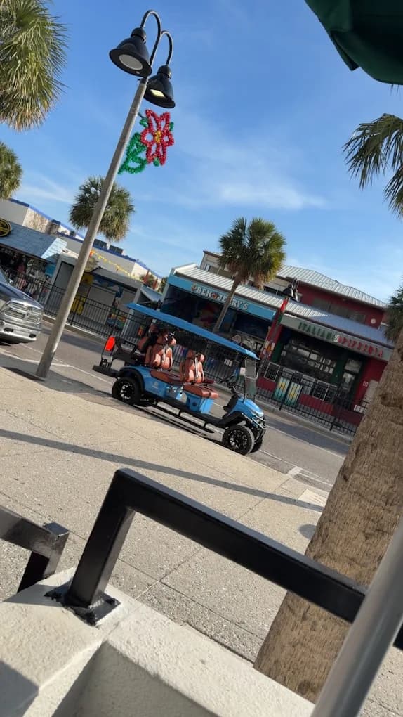 Blue luxury golf cart cruising the Clearwater Beach restaurant strip past Ben & Jerry's and the pizzeria